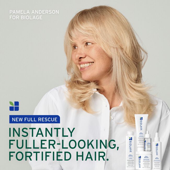 Woman with blonde hair holding Biolage hair care products against a gray background