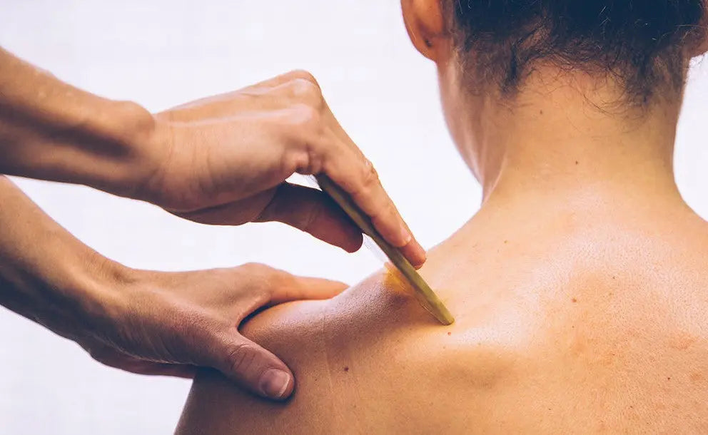 Person receiving a wooden stick massage on the back