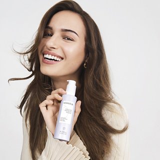 Woman holding a bottle of La Roche-Posay product against a white background