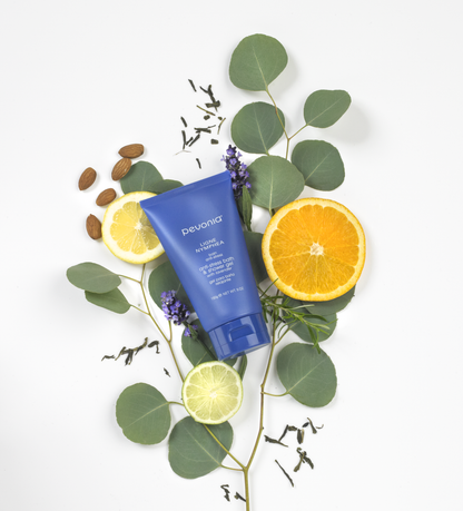 Blue skincare product with citrus fruits and leaves on a white background