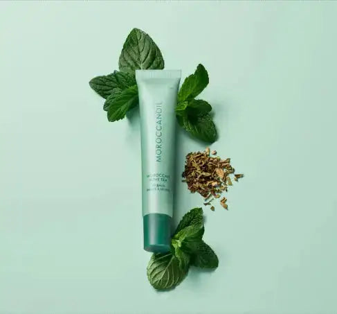 Tube of Moroccanoil product with mint leaves on a light green background