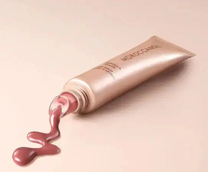 Open cosmetic tube with pink cream spilling out on a beige background