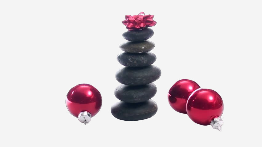 Stack of black stones with a pink flower on top, surrounded by red ornaments on a white background